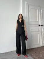 Siyah keten yelekli takım, tokalı smokin ceket ve düz pantolon kombinasyonu.