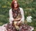 woman in white cardigan sitting on pink textile on green grass field during daytime